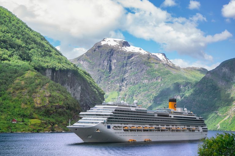 A grand cruise ship navigates the serene Geiranger Fjord in Norway, surrounded by majestic mountains.