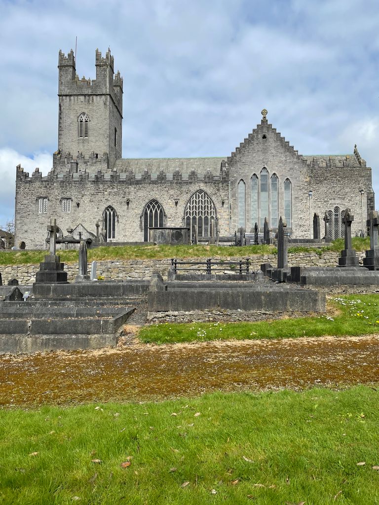 Historic stone cathedral with graveyard, showcasing medieval architecture on a bright day in Ireland.