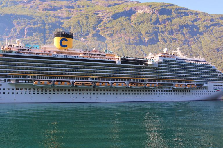 Scenic view of a cruise ship in a Norwegian fjord with green mountains.